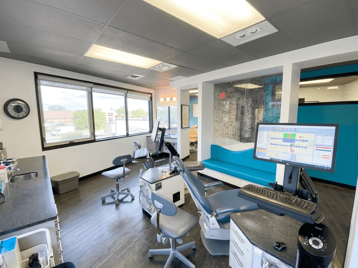 A treatment station beside the windows, with a chairside monitor and scheduling screen